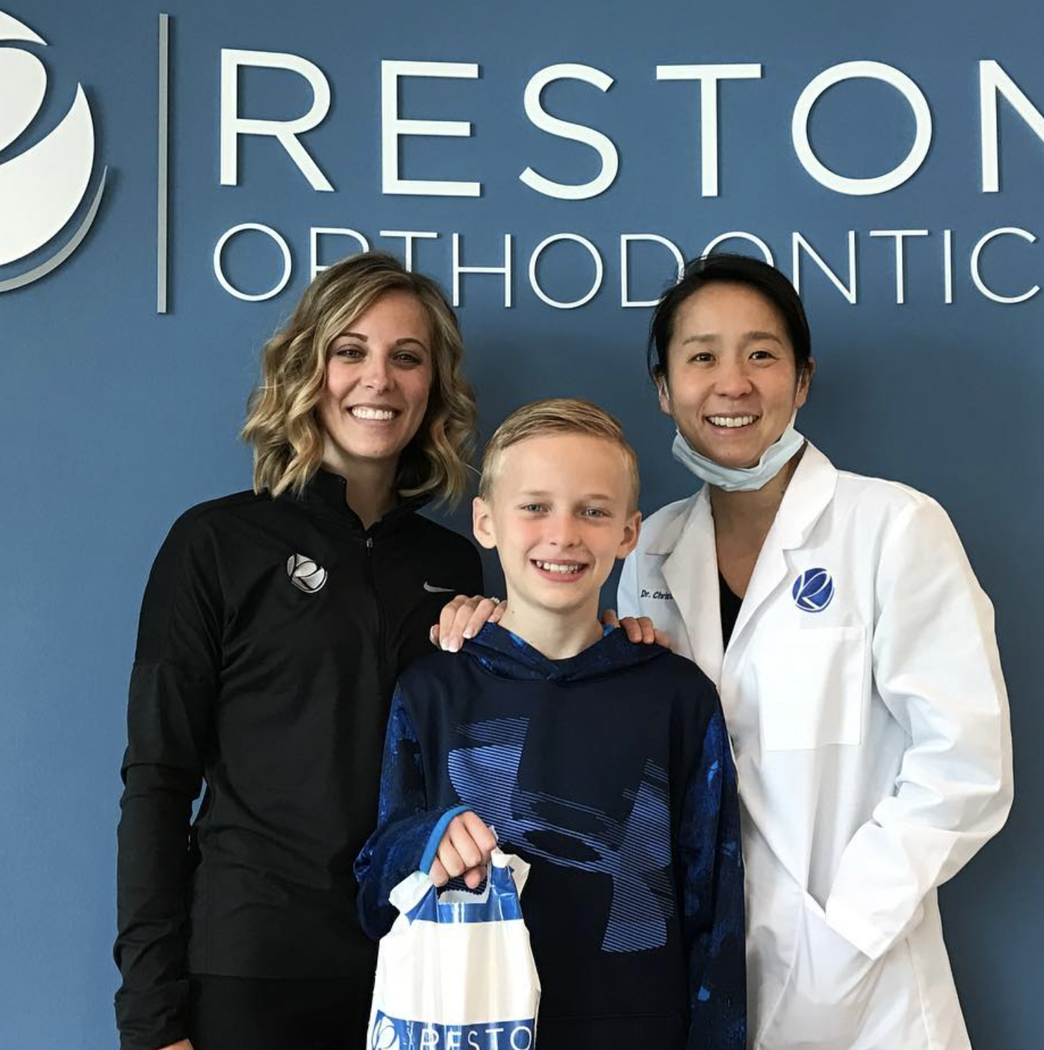 A young patient celebrating with Dr. Kim and a Reston Orthodontics team member